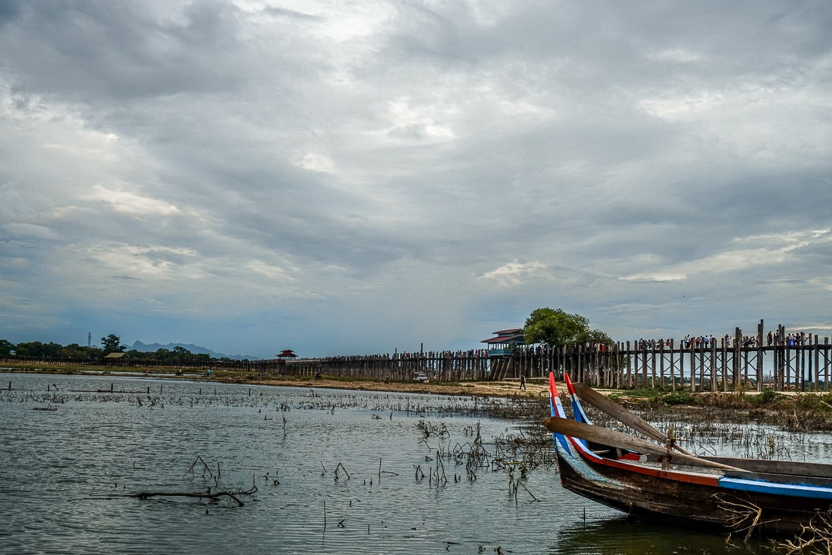 A wooden bridge over a shallow river with rowing boats