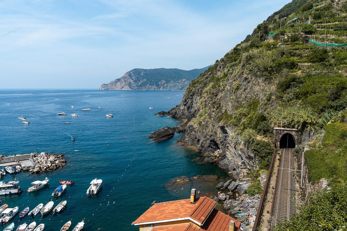 A viewpoint of cliffs, sea, and a train track running through a tunnel
