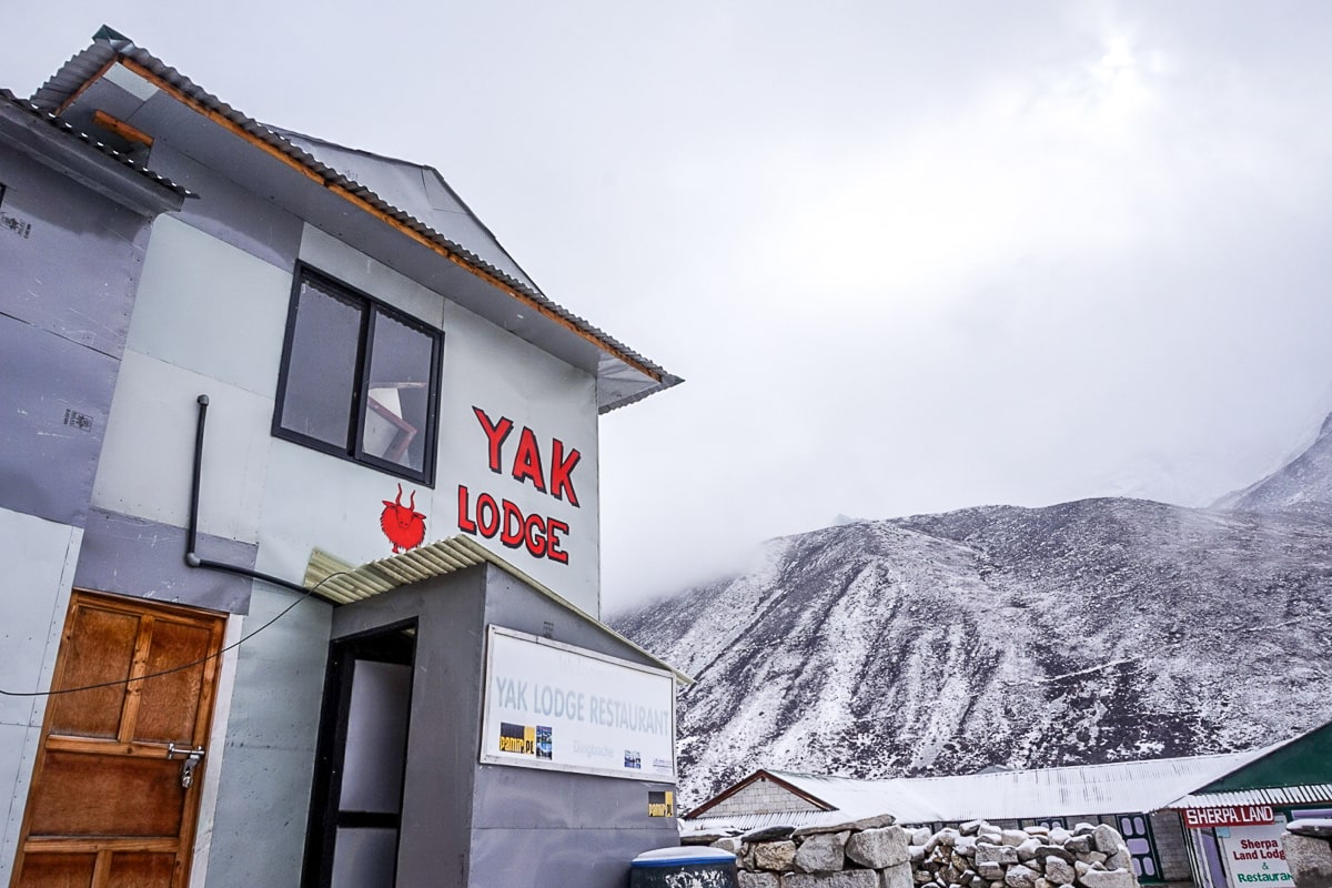 A hotel with Yak Lodge painted in red on the side with a snowy mountain in the background