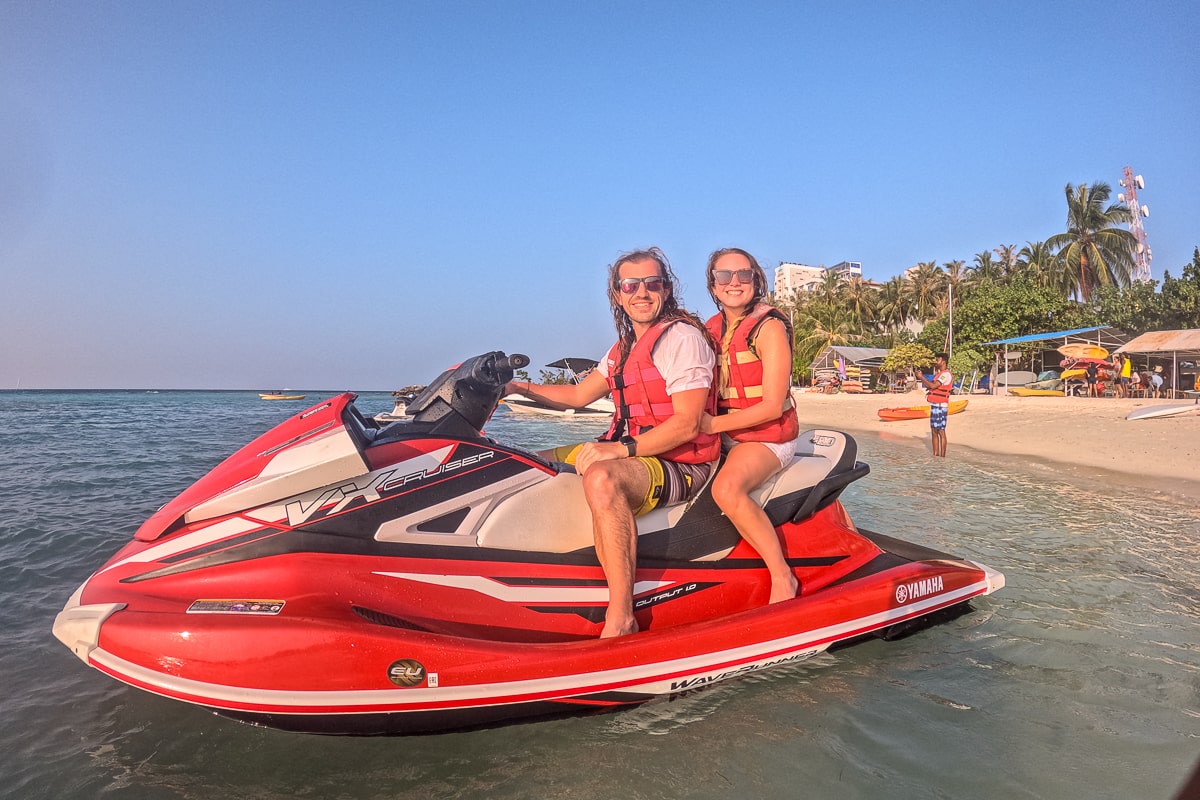 A couple sat on a jet ski in the shallow water near the beach