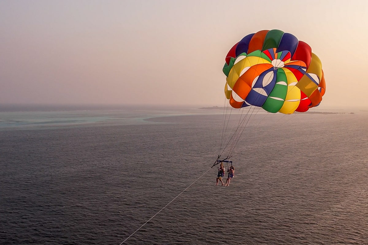A couple parasailing at sunset above the ocean
