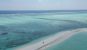A couple walk on a sandbank seen from very high up drone shot