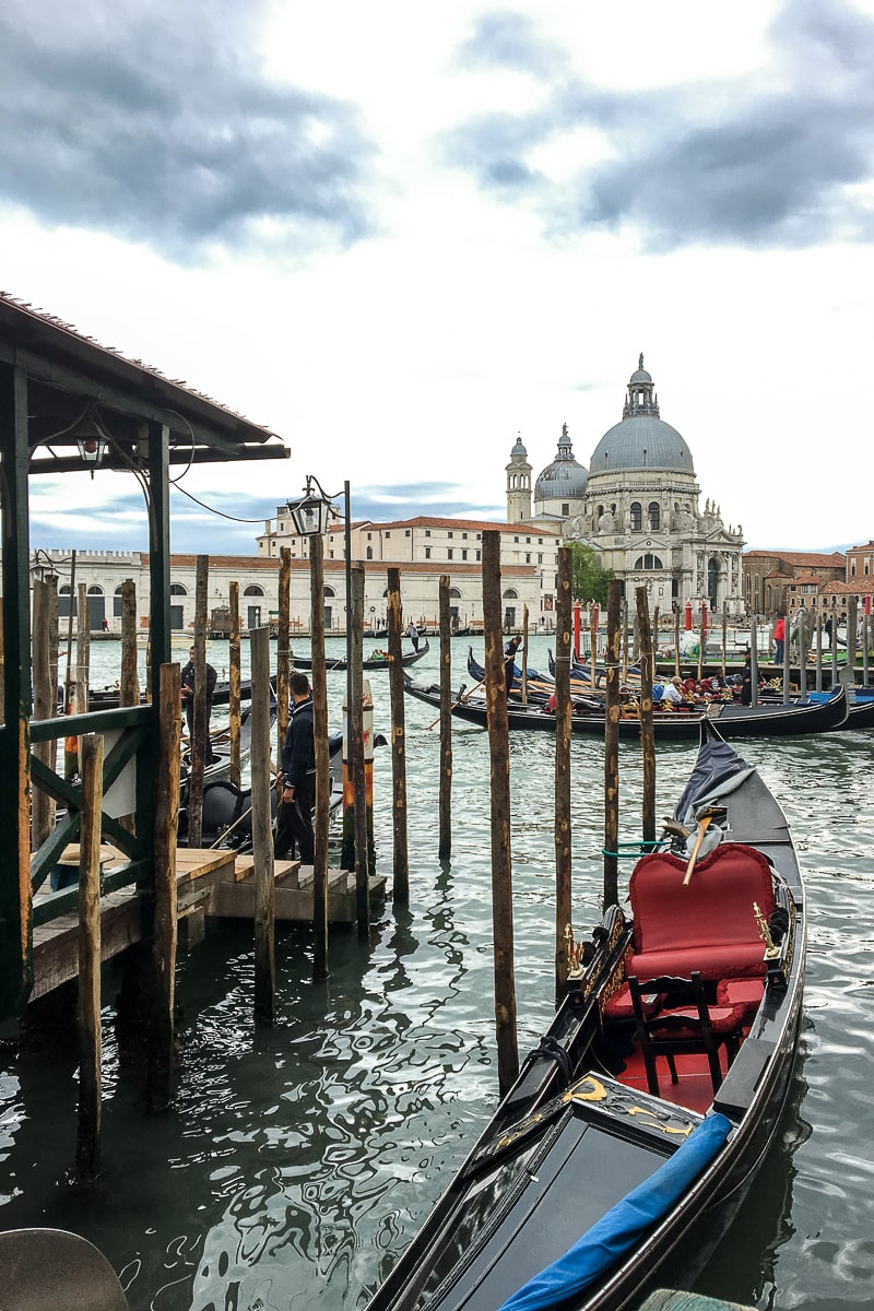 A venetian gondola with red seats and tall wooden poles used for tethering boats
