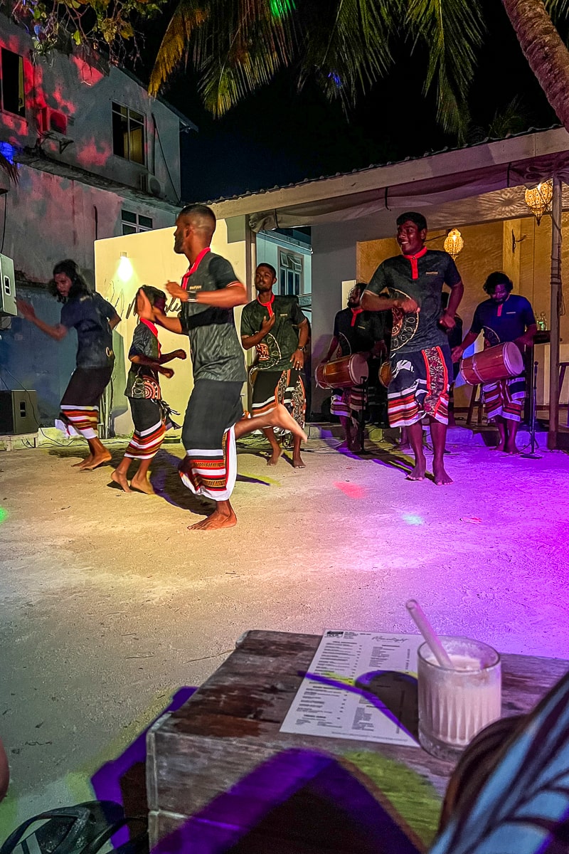 A group of men in traditional Maldivian dresses performing a local dance at a beach club