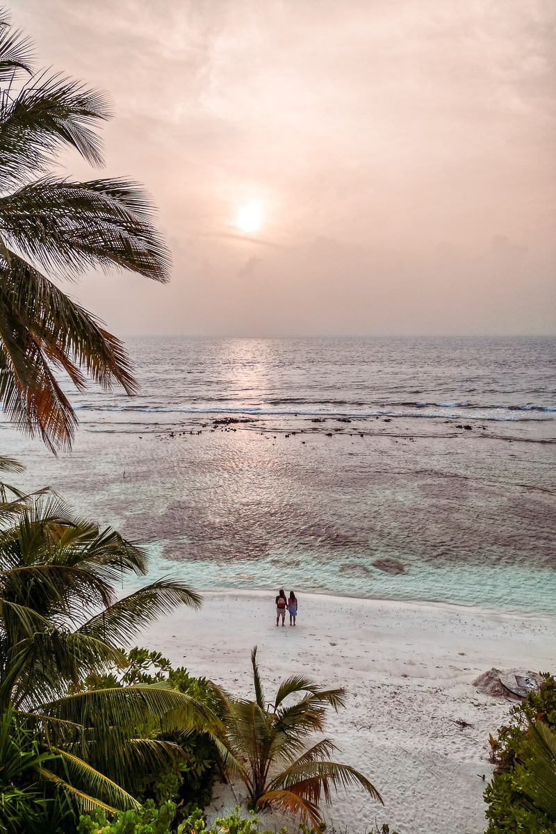 A couple stood watching the sunset on a beach in Dhigurah