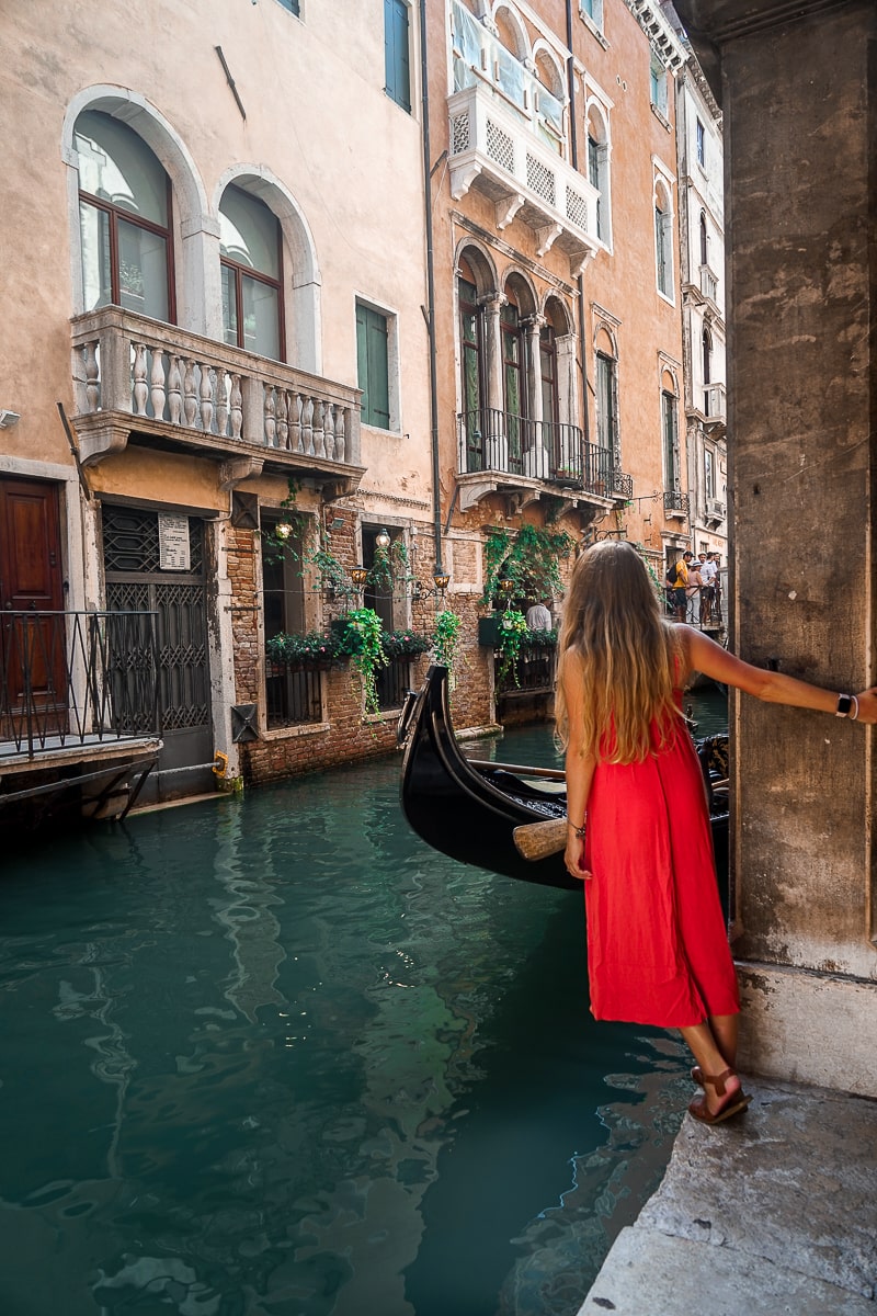 A woman in a red dress leaning over a Venetian canal