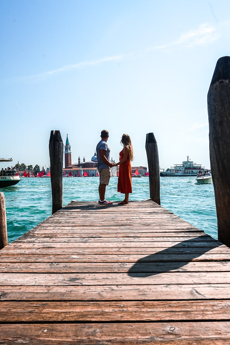 A couple stood at the end of a wooden pier holding hands