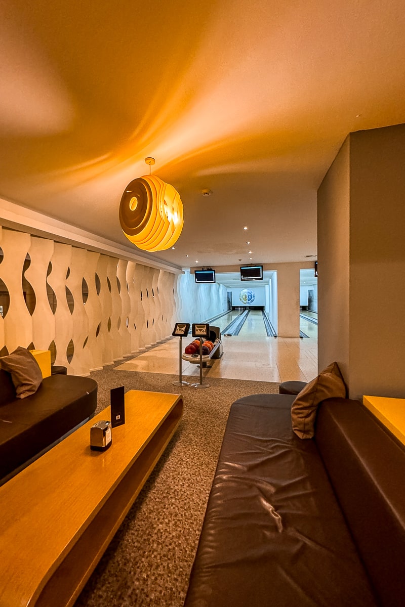 A warmly lit bowling alley with leather sofas