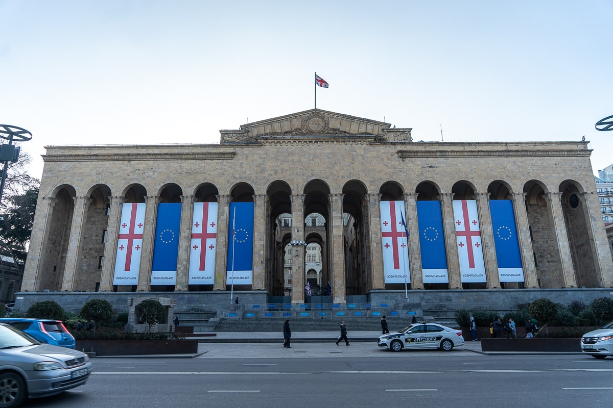 The Georgian parliament building in Tbilisi - A grand beige stone building with high arches