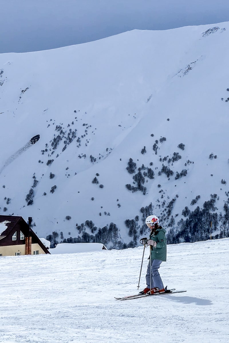 A girl skiing down a freshly groomed slope with a large snowy mountain looming behind