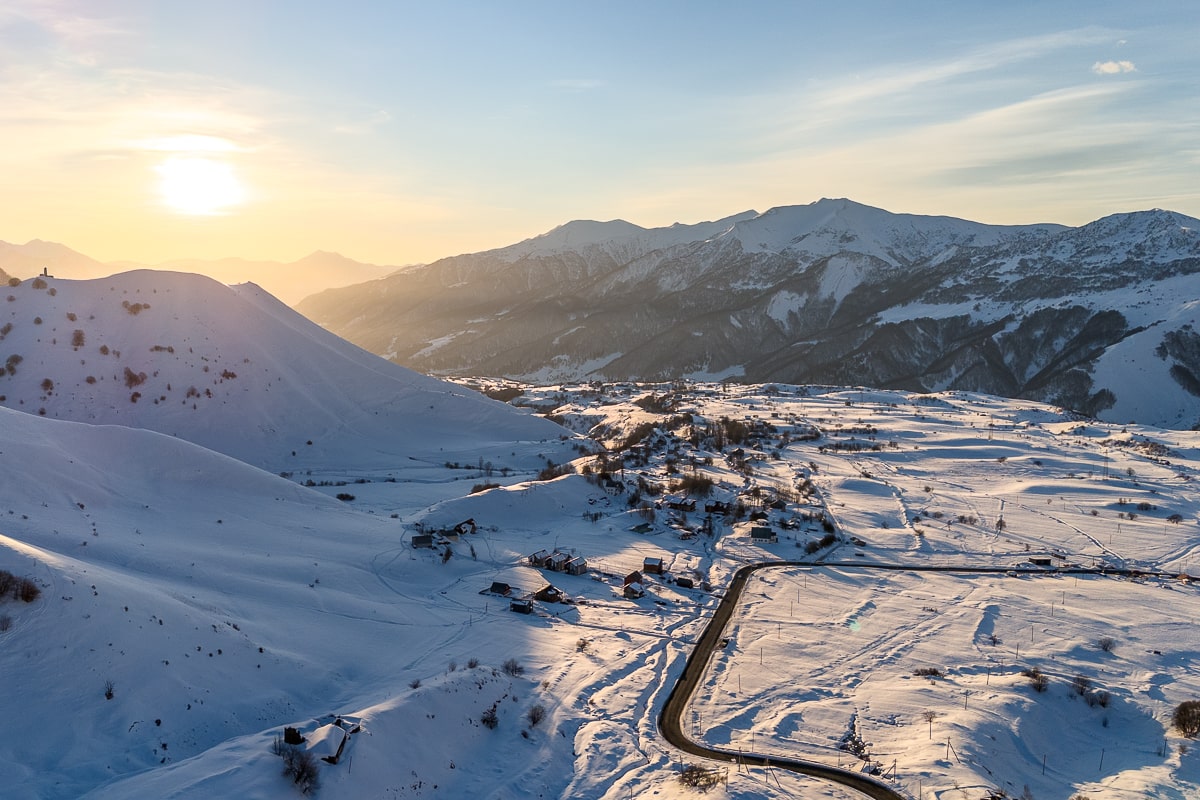A landscape shot of snowy mountains and a small town in the northern Caucasus region of Georgia