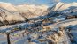 An aerial landscape shot of a snow-covered Gudauri bathed in soft, morning sunlight