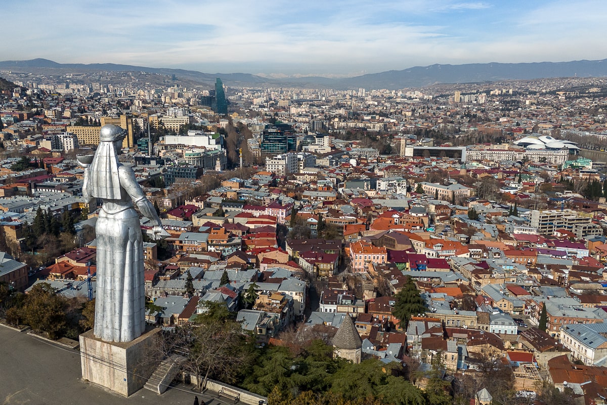 A wide shot of Tbilisi with the Mother of Georgia statue - a large aluminium statue of a woman - overlooking the city