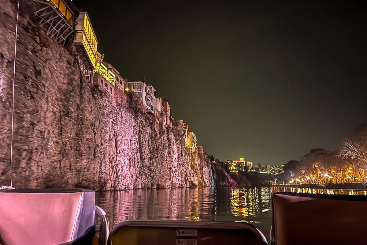 A river cruise with a very large, vertical cliff with houses perched on top