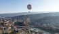 A panoramic shot of Tbilisi with the river featuring prominently and a hot air balloon in the sky