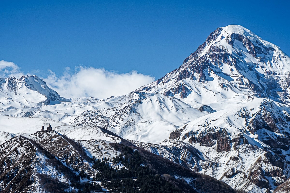 An orthodox church dwarfed by a snow-capped mountain