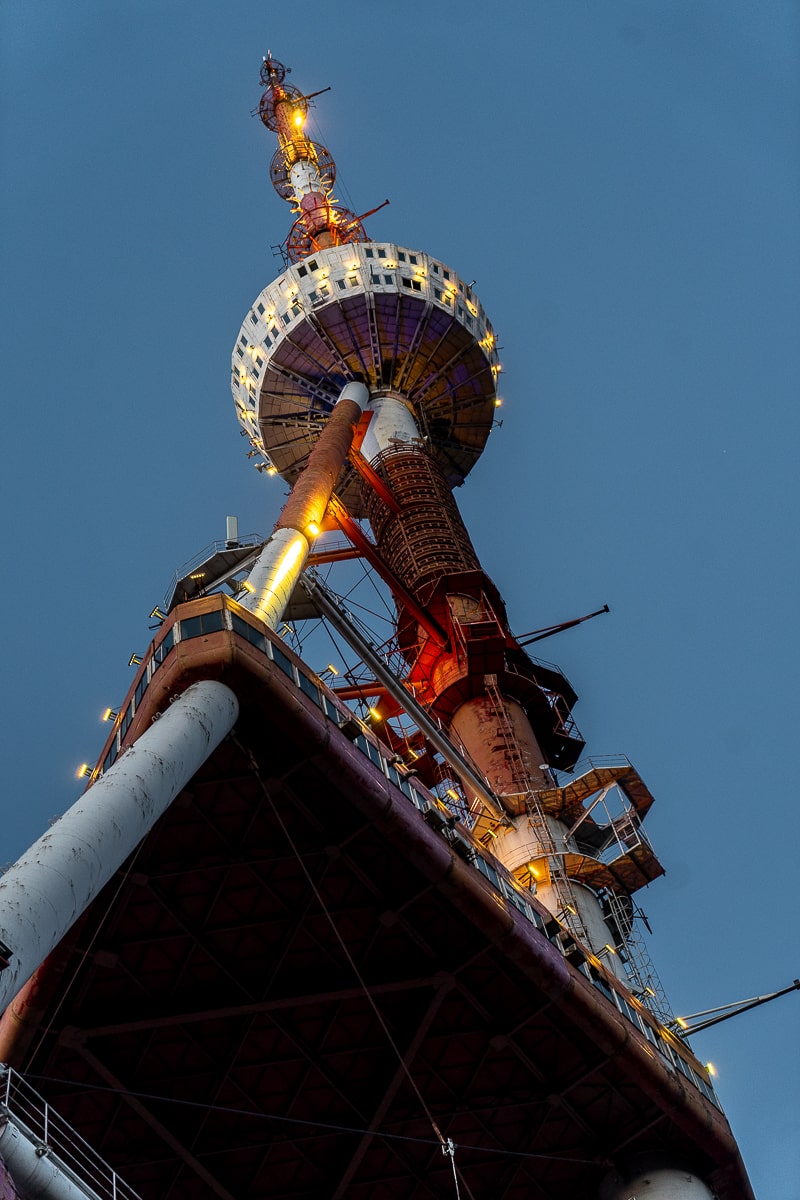 A tall, red and white TV tower stretching up to the sky from directly underneath