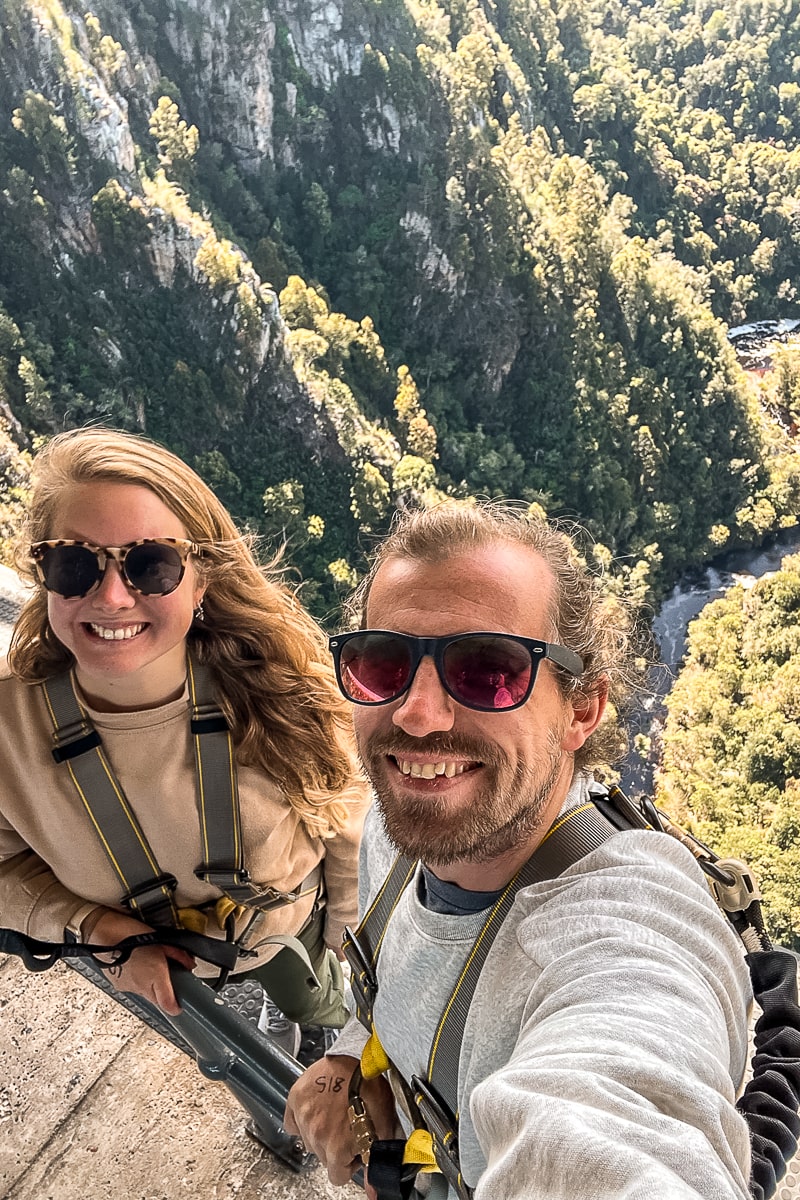 A couple with a huge drop to a tree covered ravine behind