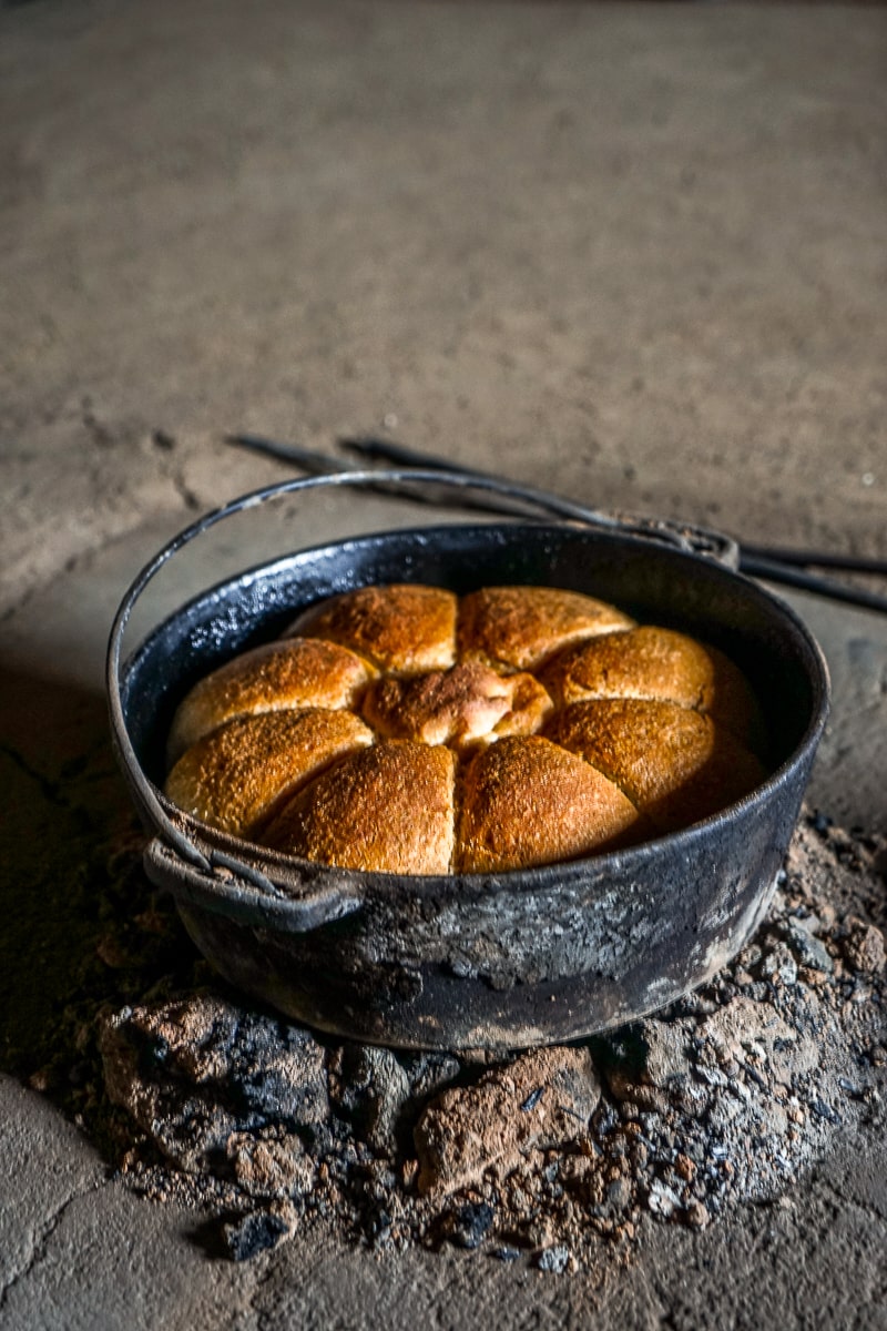 A circular pan of bread on a charcoal fire pit