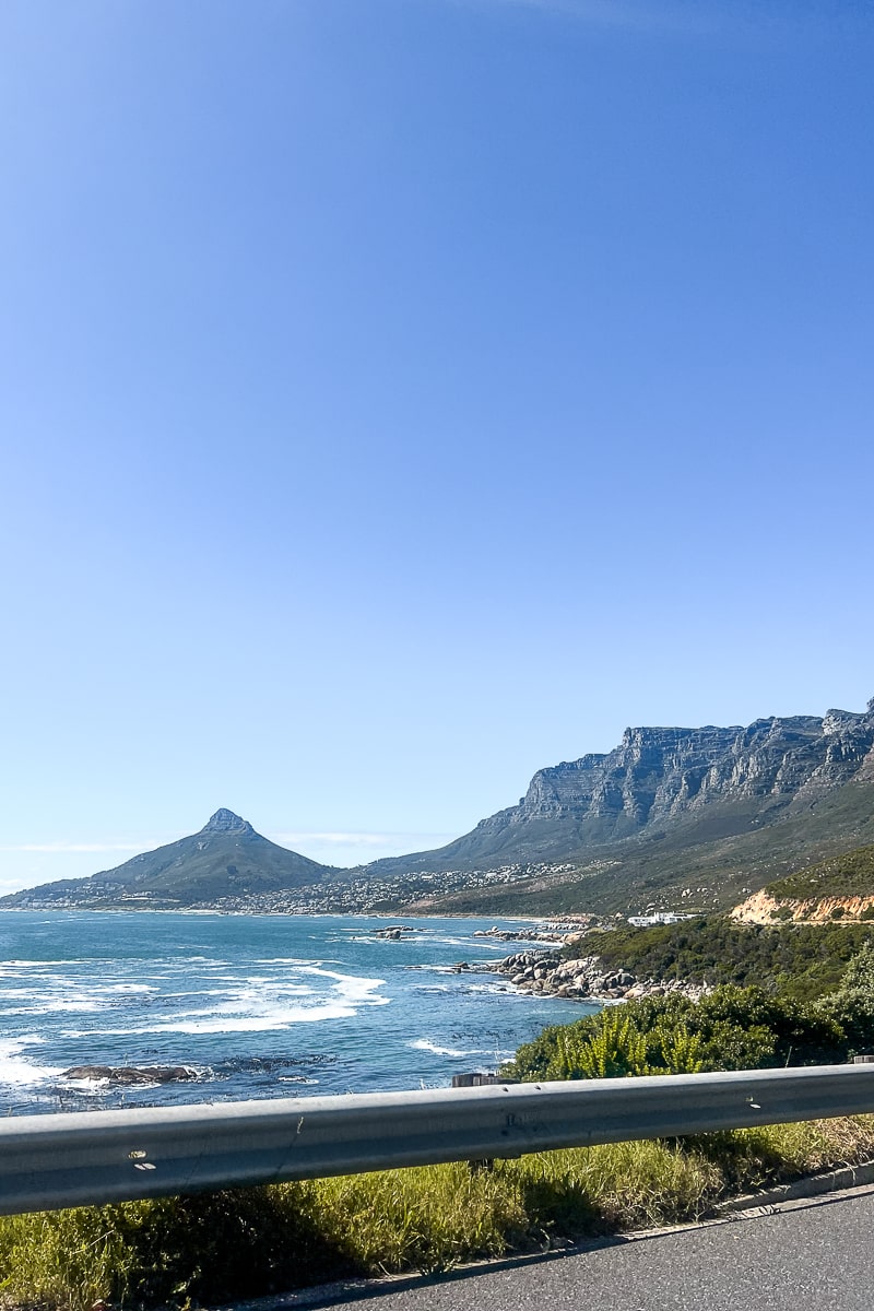 An ocean view from a car with large mountains in the background