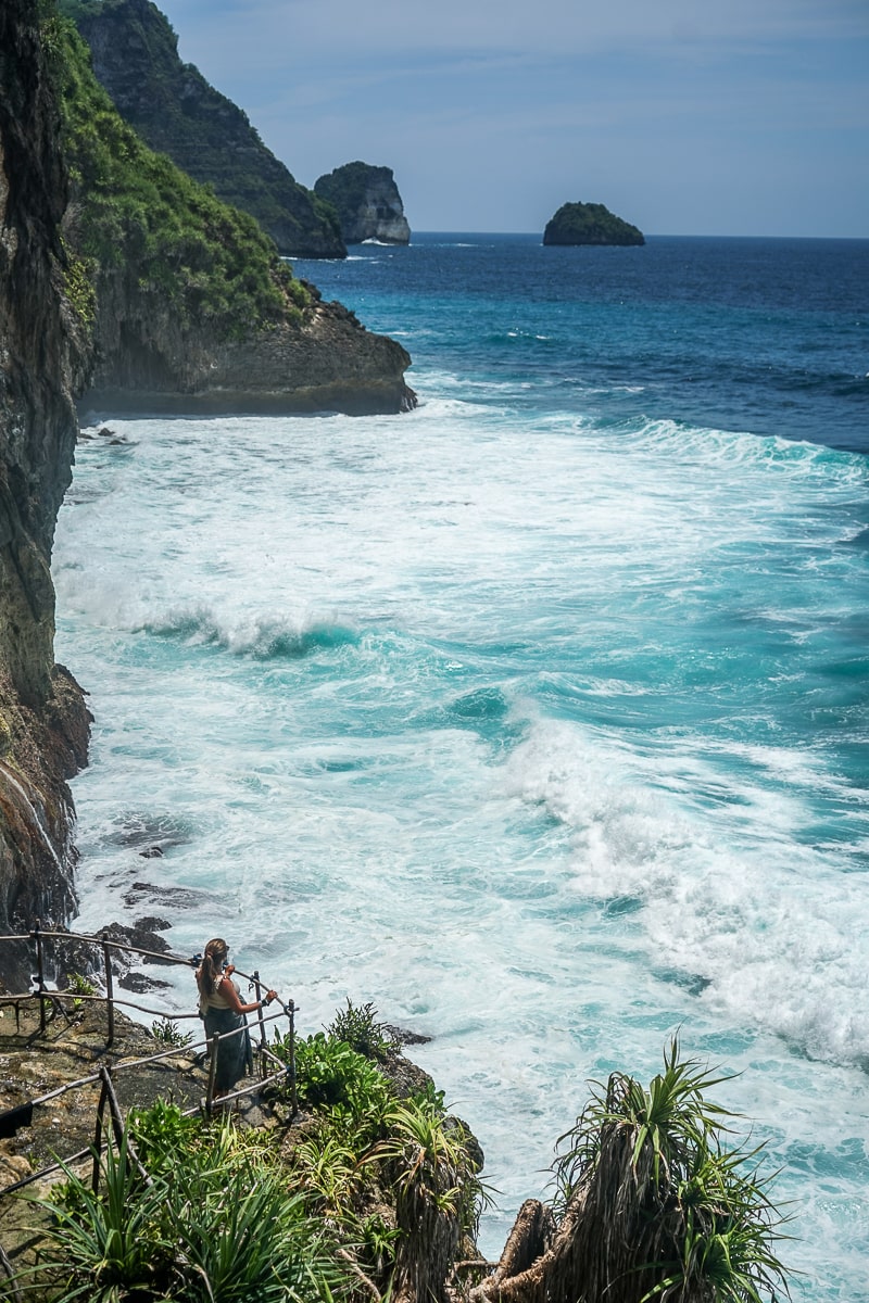A woman standing watching the rough ocean from a cliff viewpoint