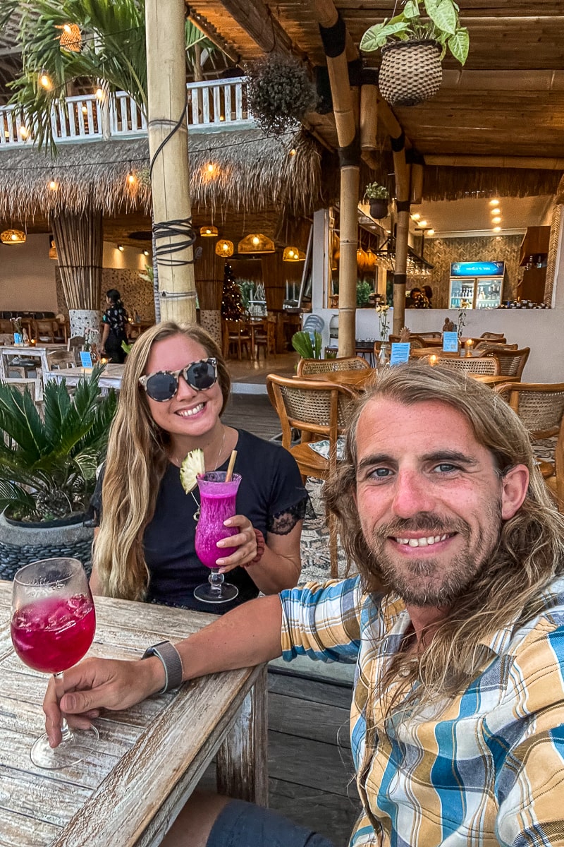 A selfie of a couple enjoying pink and red cocktails in a beach bar