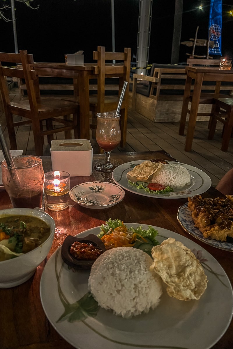 A dinner table at a beach restaurant with plates of rice and curries