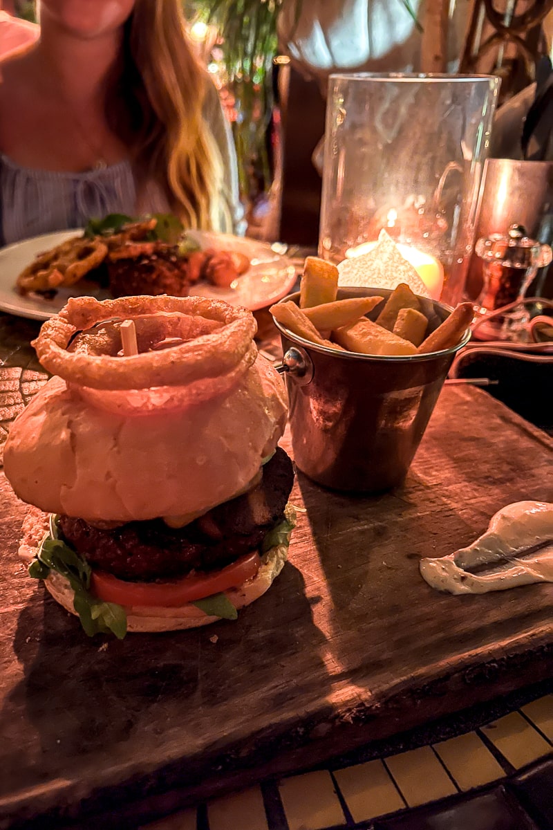 A gourmet burger with onion ring on top and chips