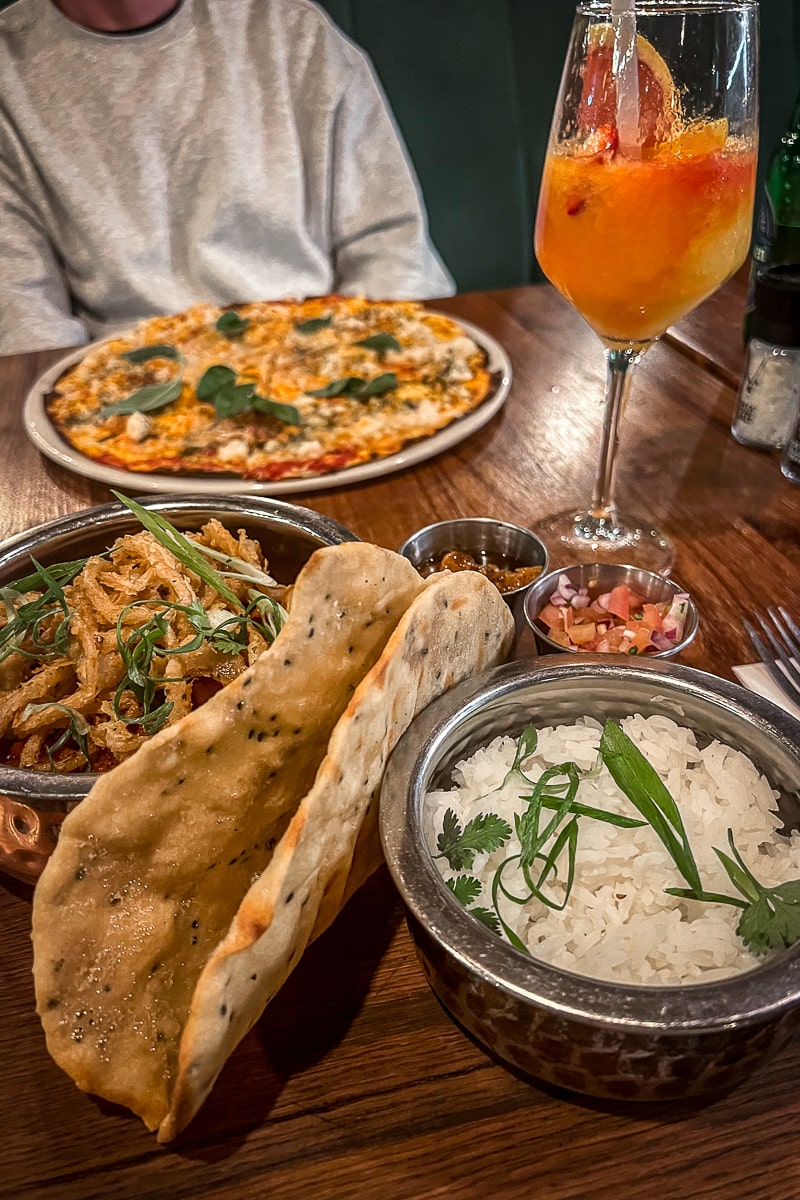 A curry with naan bread, pizza, and cocktails