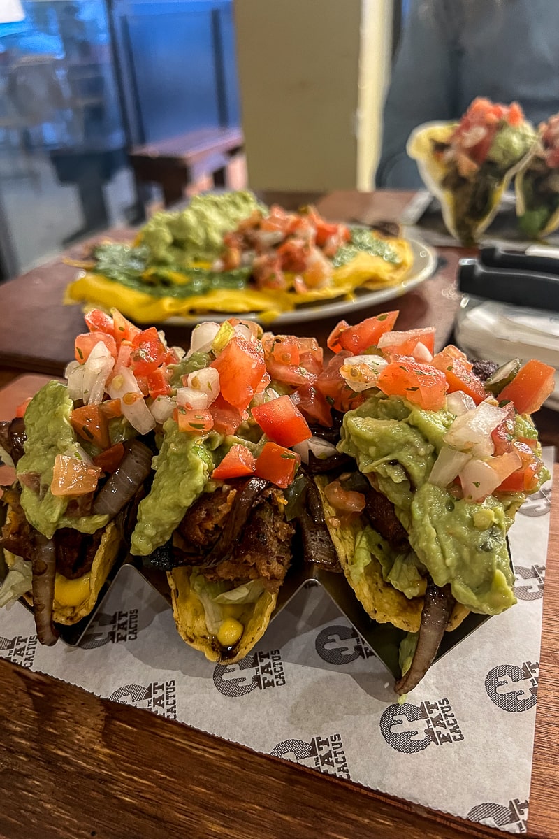 Three tacos with salsa and guacamole piled on top