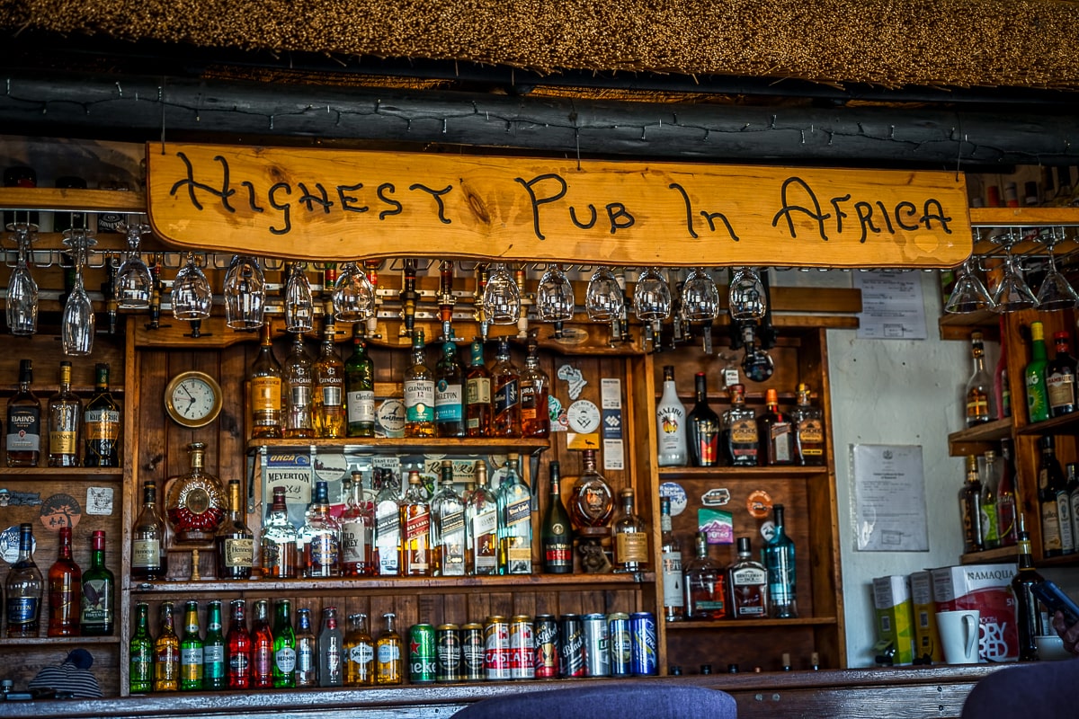 A well stocked wooden bar with a sign reading "Highest Pub In Africa" above