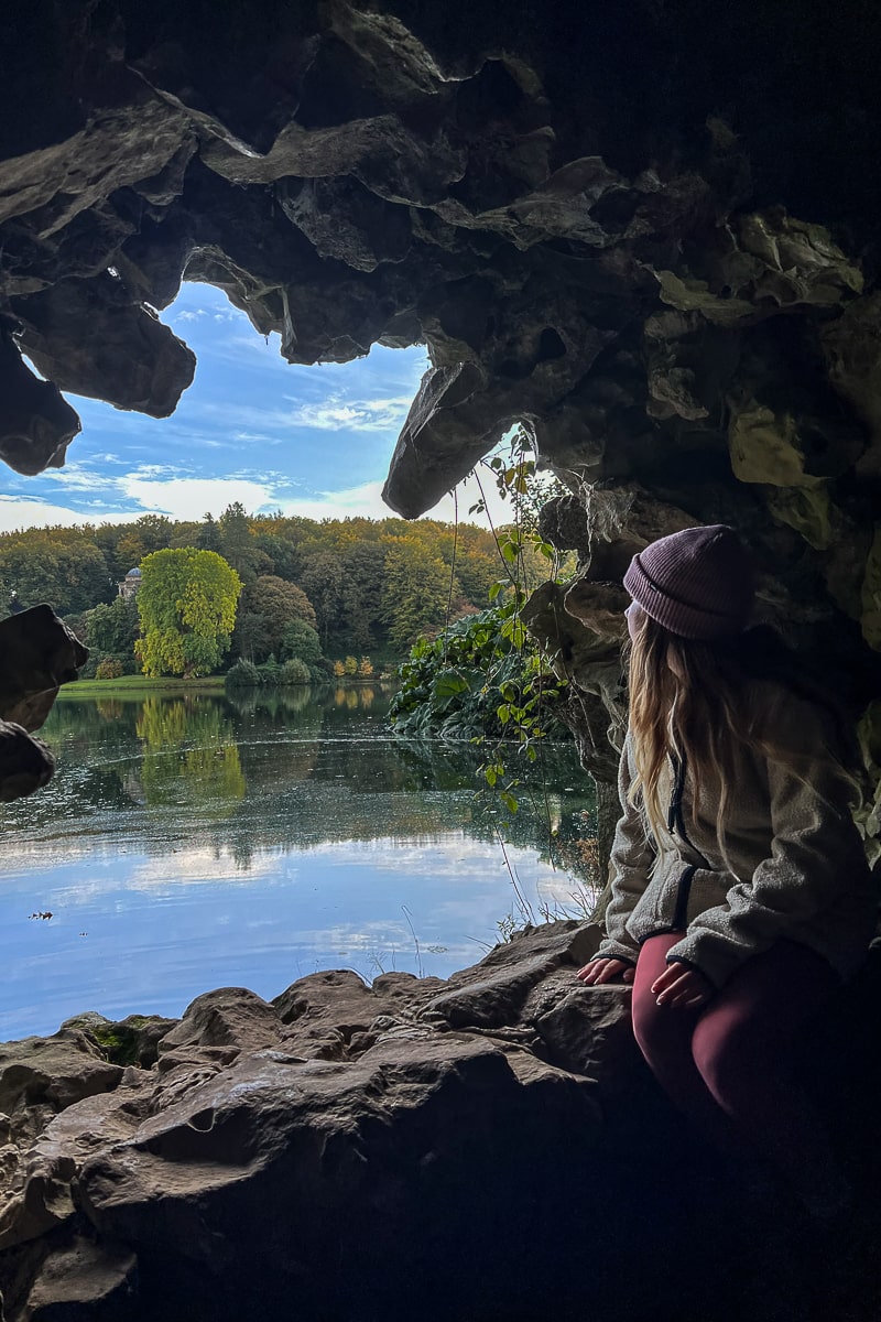 A woman looking out of a carved hole through rock in an Italian Grotto