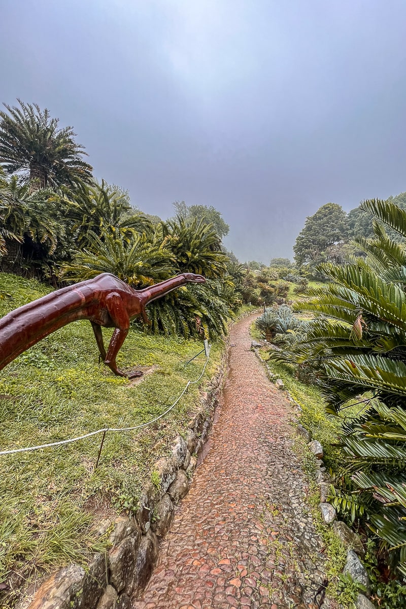 A dinosaur sculpture in a botanical garden
