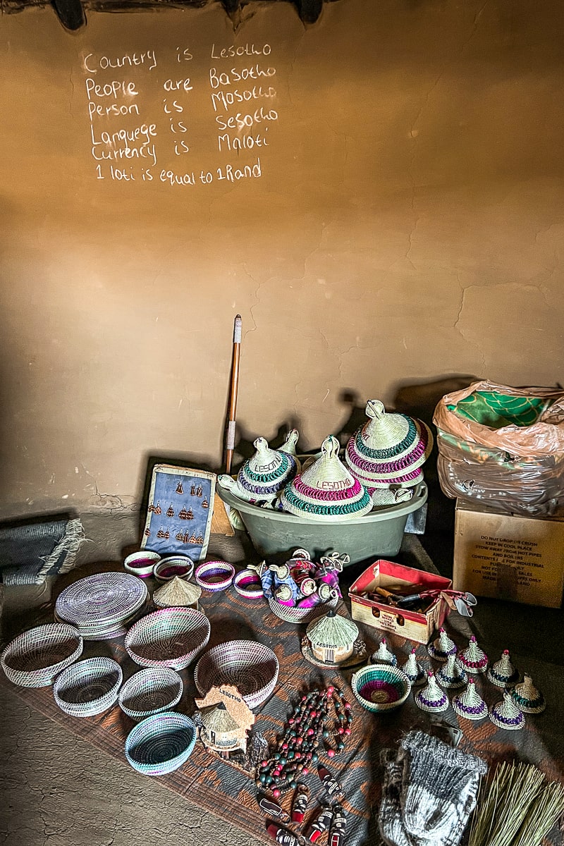Handmade crafts and souvenirs like bowls, hats, and sculptures inside a mud hut