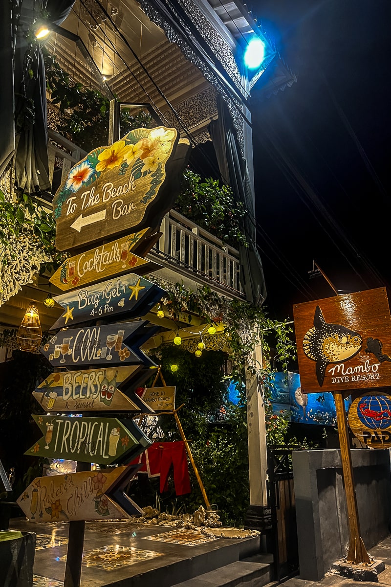 A set of rustic wooden signs pointing to a beach bar