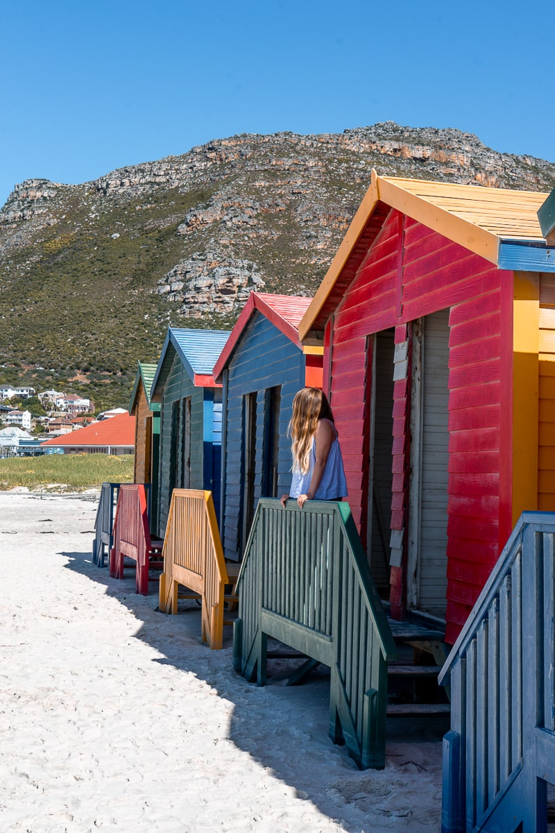 Colorful beach huts and a woman on the balcony of one