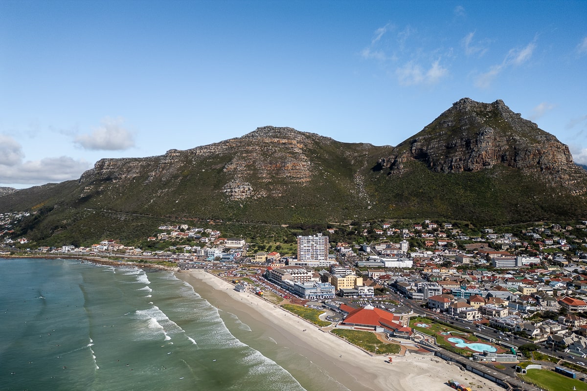 An aerial shot of a beach and town surrounded by large mountains