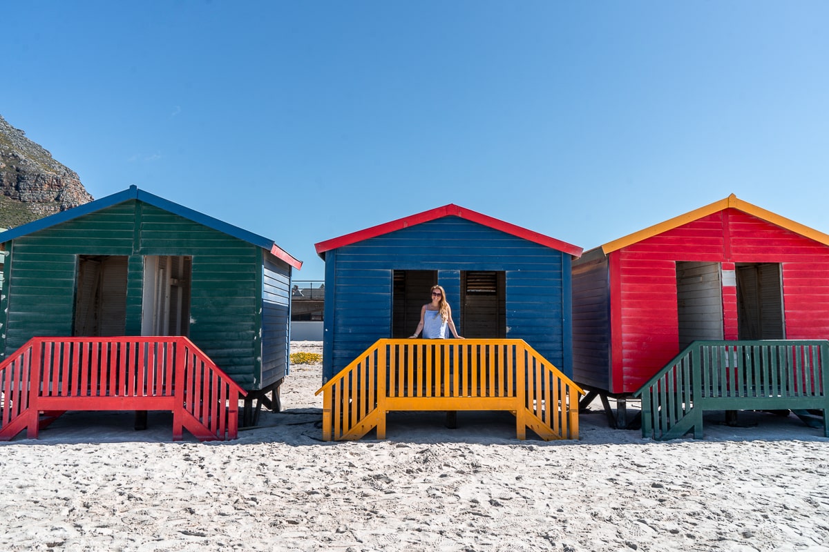 Colorful beach huts with a woman leaning on the balcony of one