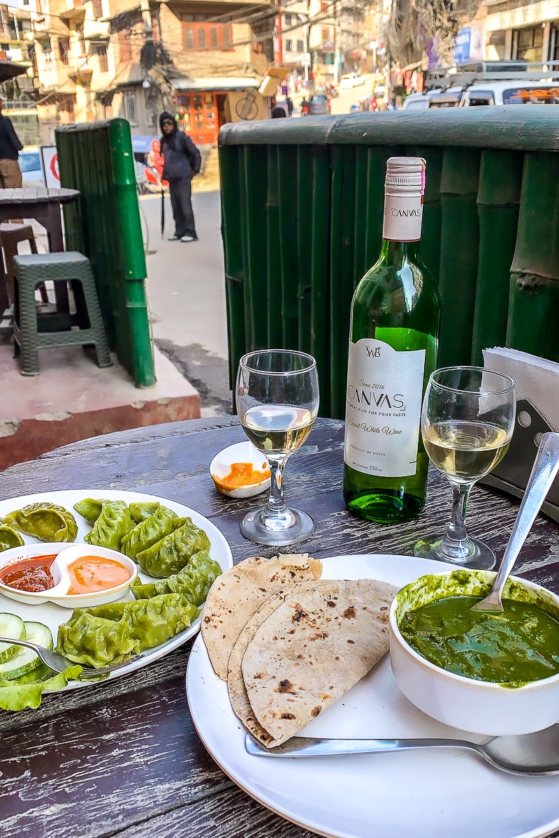 A Nepali meal of momos, sauces, curry, and chapatis outside a restaurant