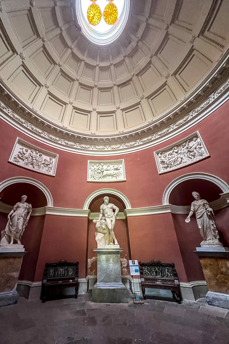 A room with intricate domed ceiling with Greco-Roman statues beneath