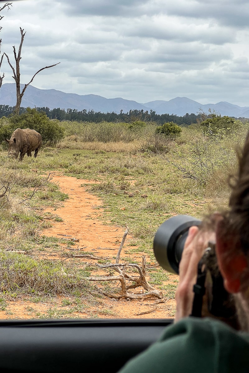 A man taking a photo on a long lens of a rhino in Kruger