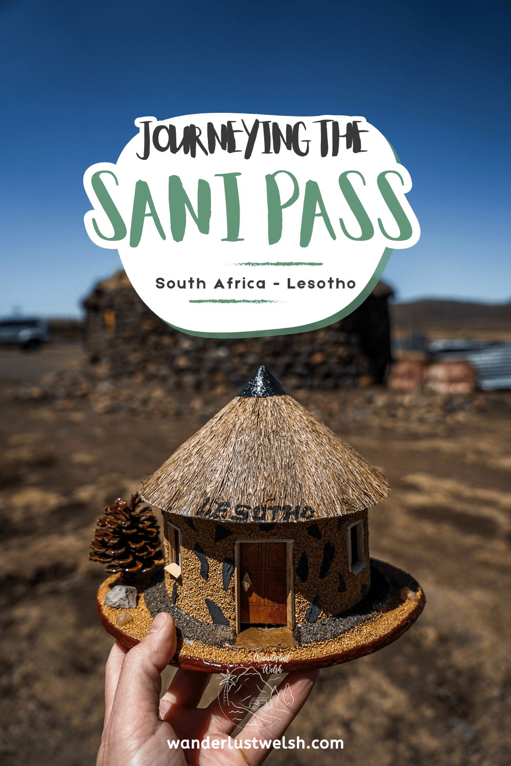A miniature handcrafted traditional Lesotho hut with the words "Journeying the Sani Pass" superimposed