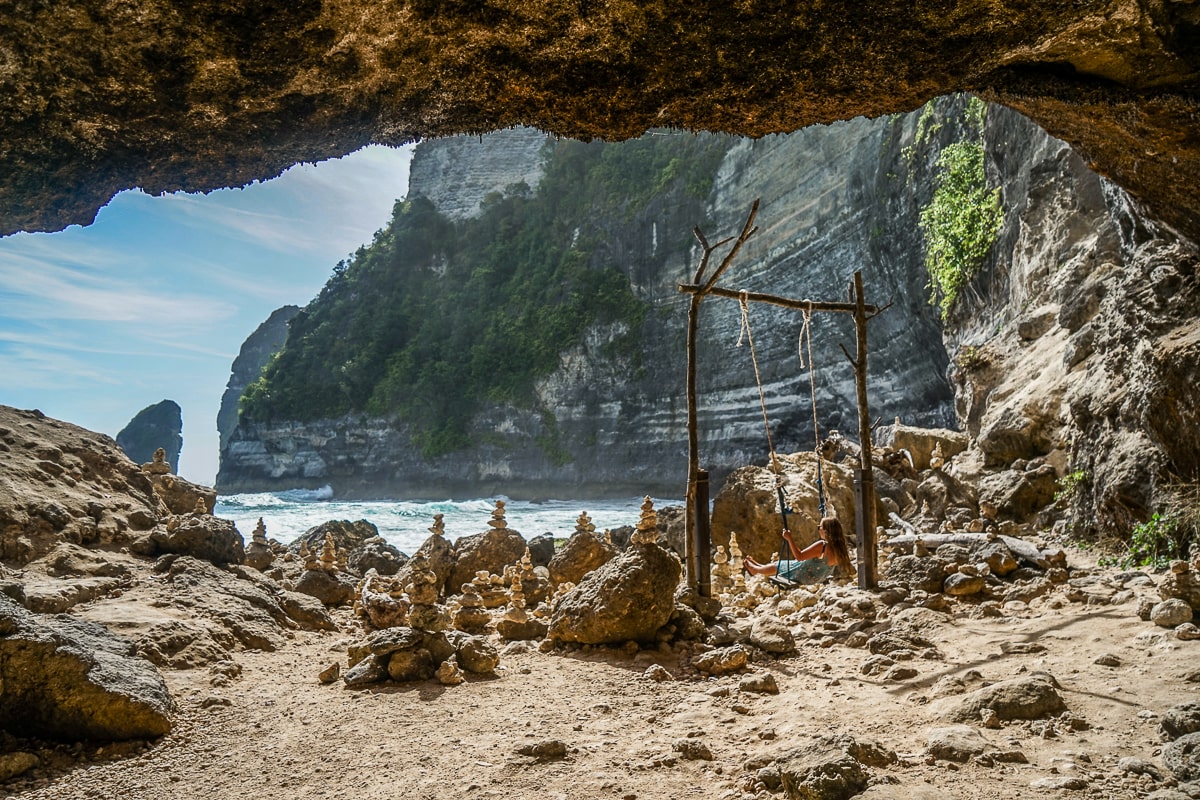 A woman swinging on a secluded cove beach with many stone stacks