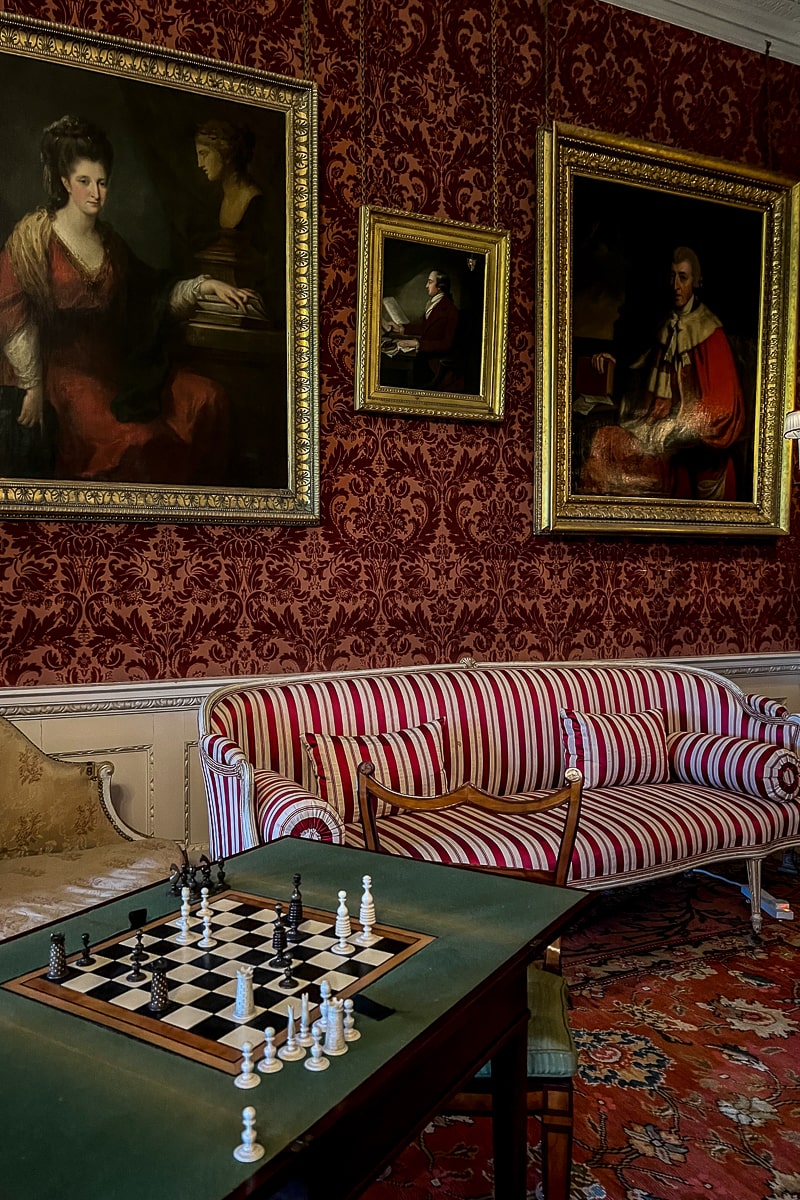 A room adorned with portraits and an antique chess board