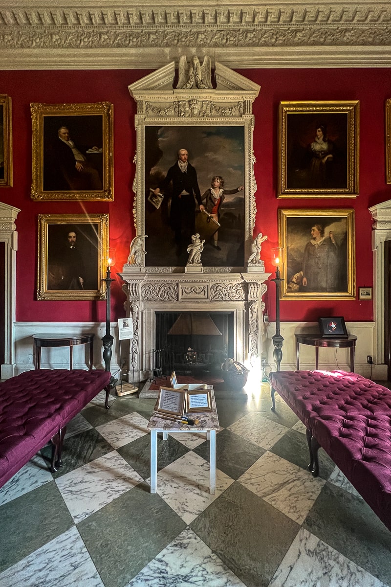 A lavish room with large portraits and white fireplace