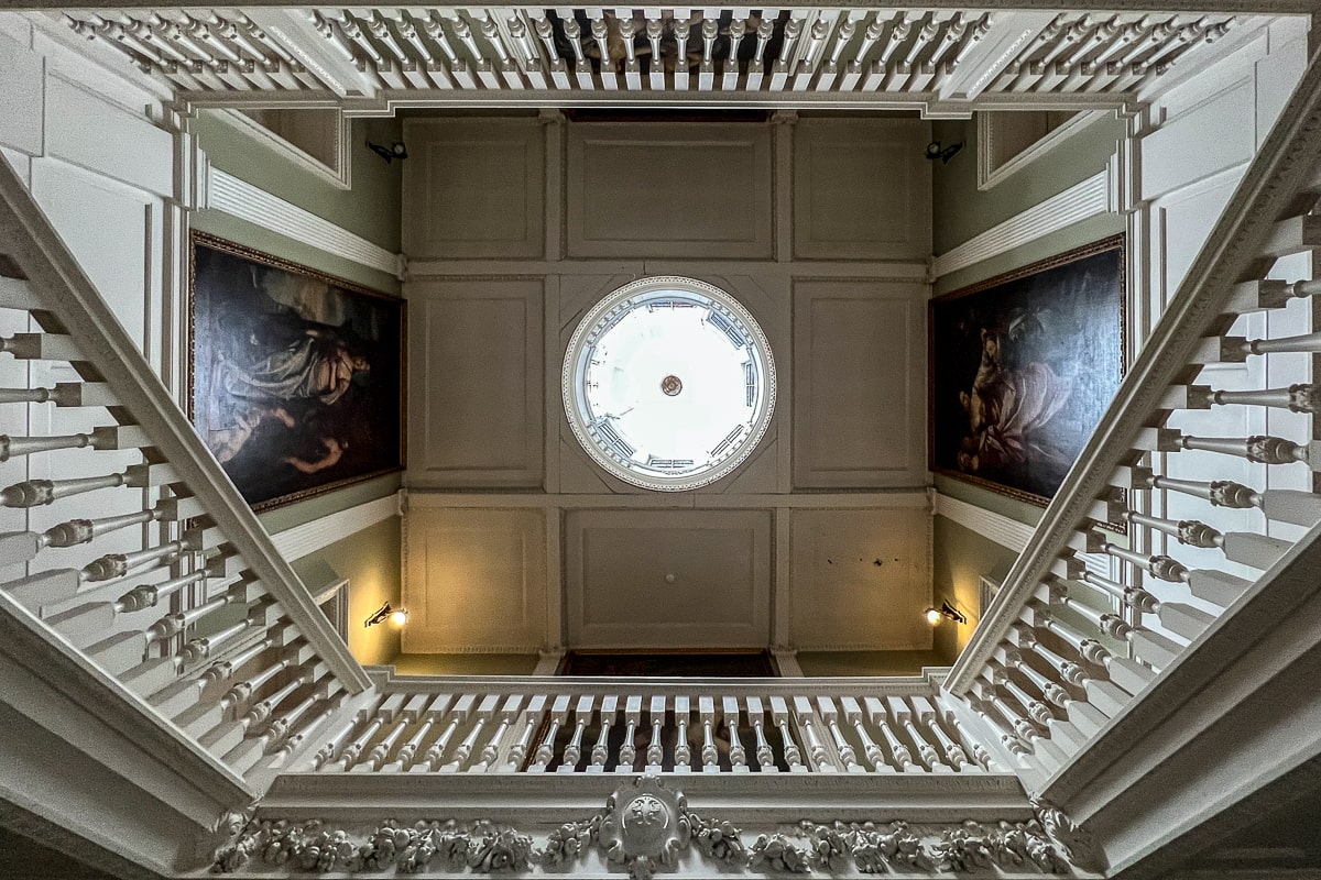 The ceiling of a lavish house with huge portrait paintings and staircases