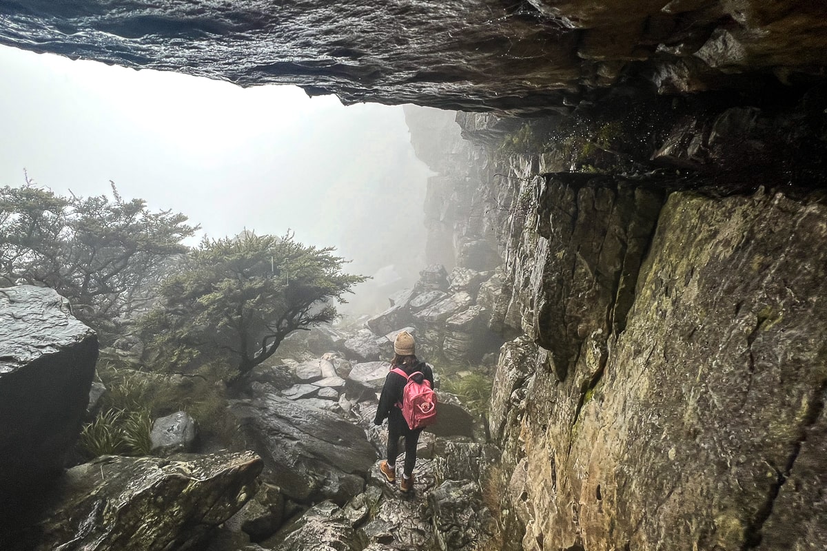 A rock overhang with a woman walking on the path below