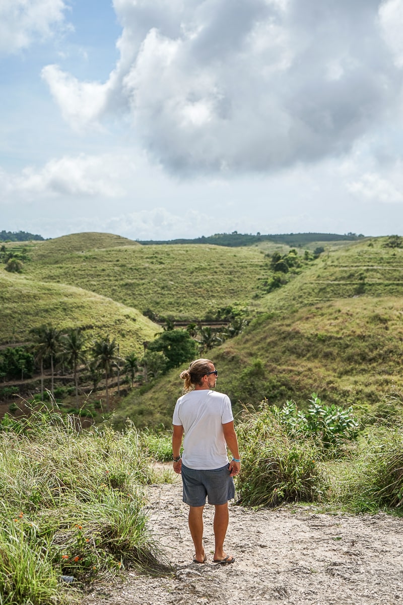 A man standing looking out over rolling green hills