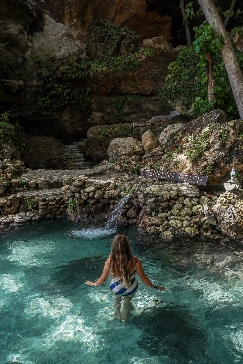 A woman bathing in a crystal clear pool in a forest setting