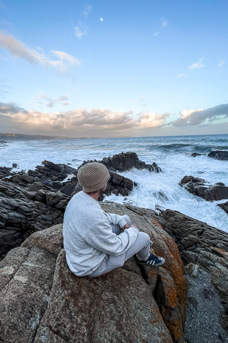 A man sat on a rocky shoreline